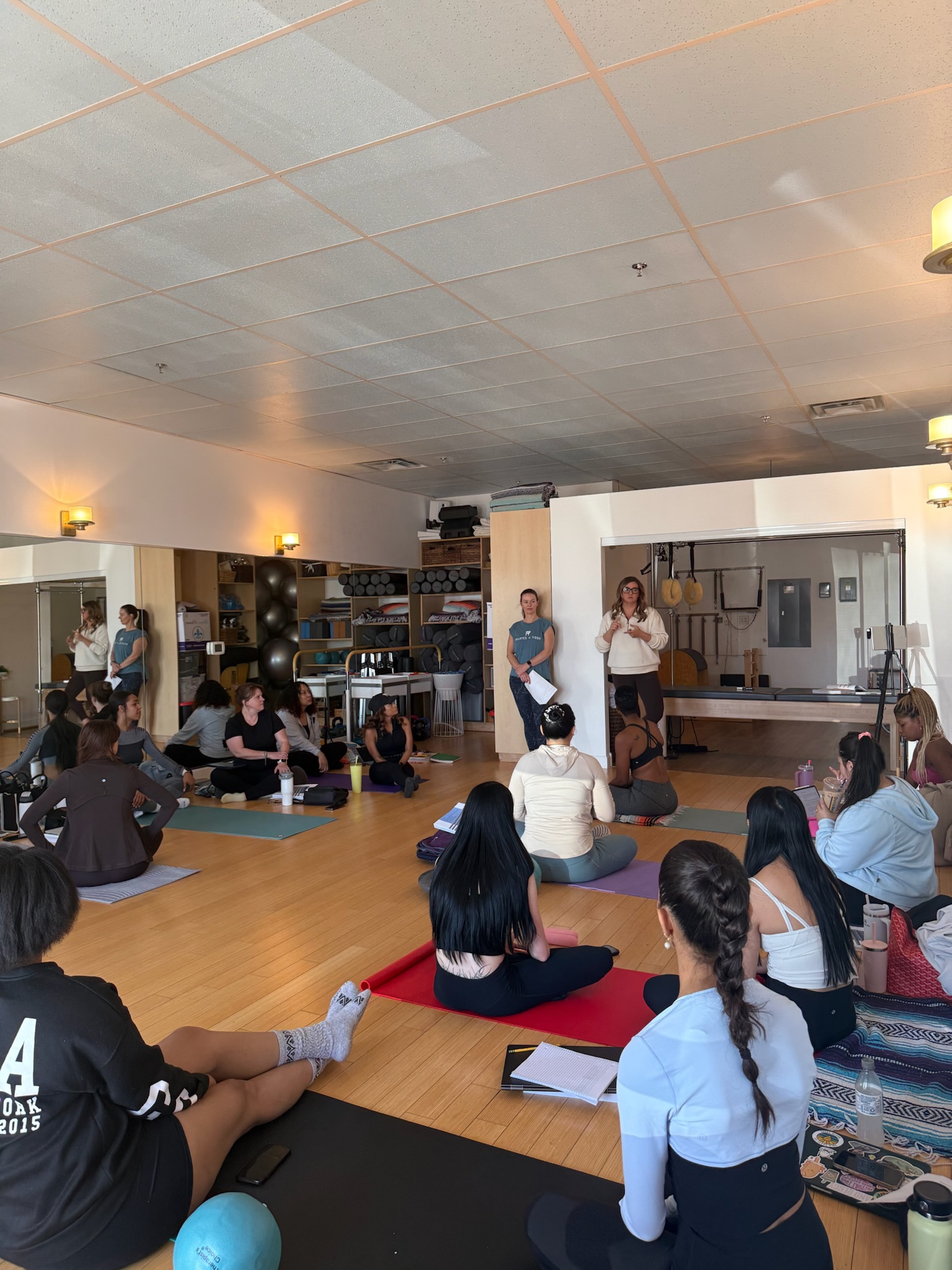teacher teaching Pilates Teacher Training students on the mat