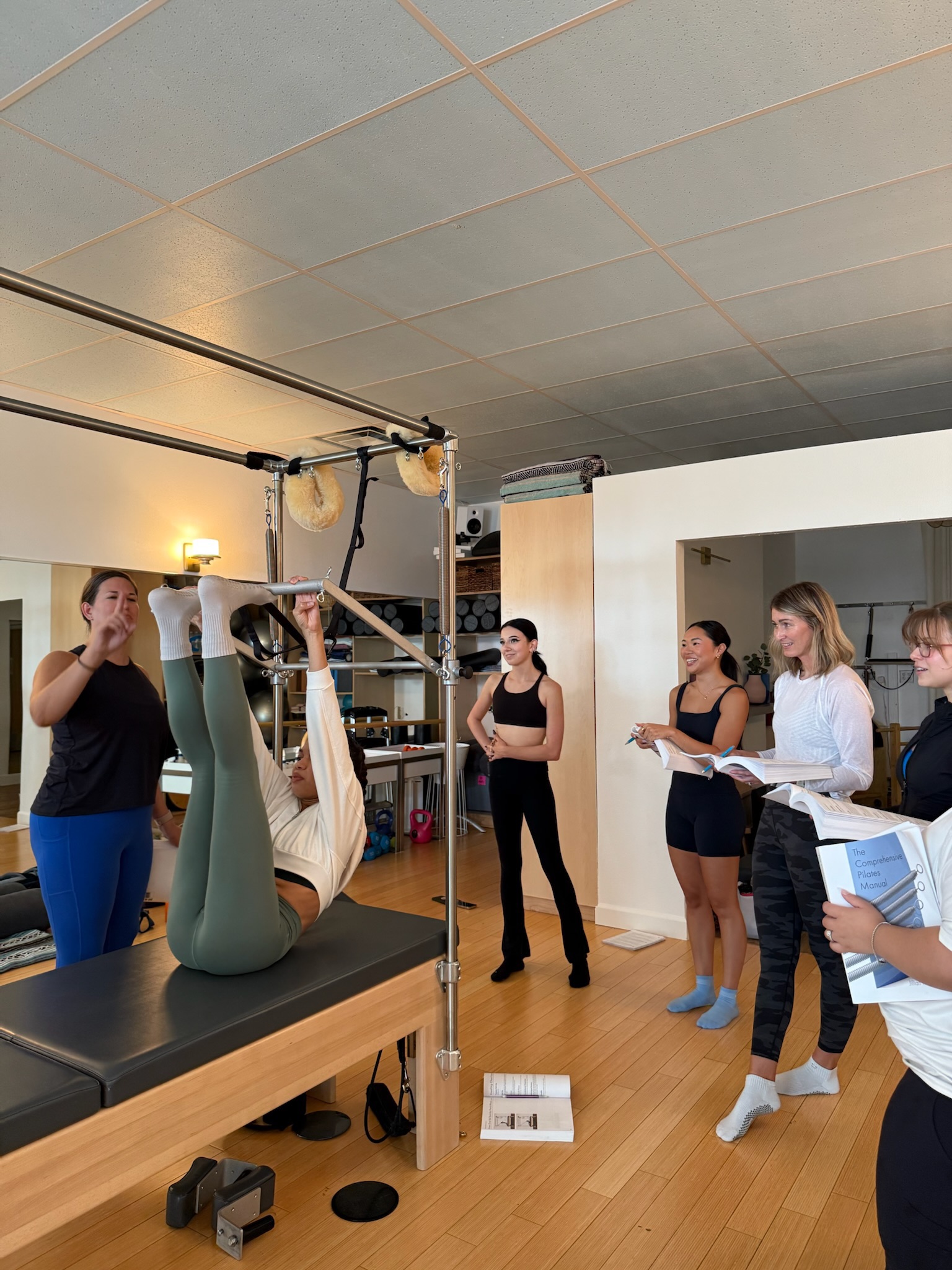 Pilates Teacher Training students practicing monkey on the cadillac/trapeze table