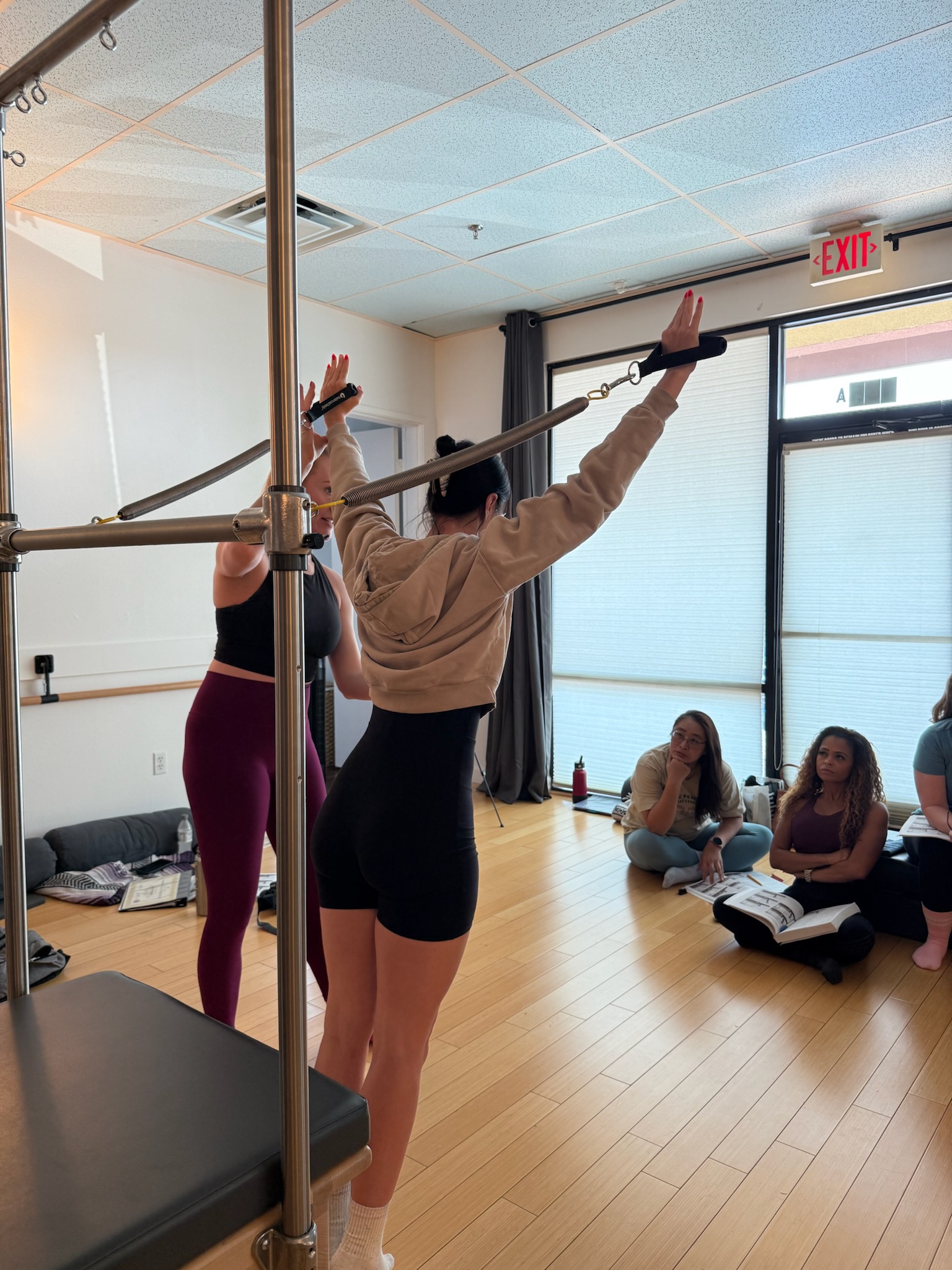 Pilates Teacher Training students practicing arm series on the cadillac/trapeze table