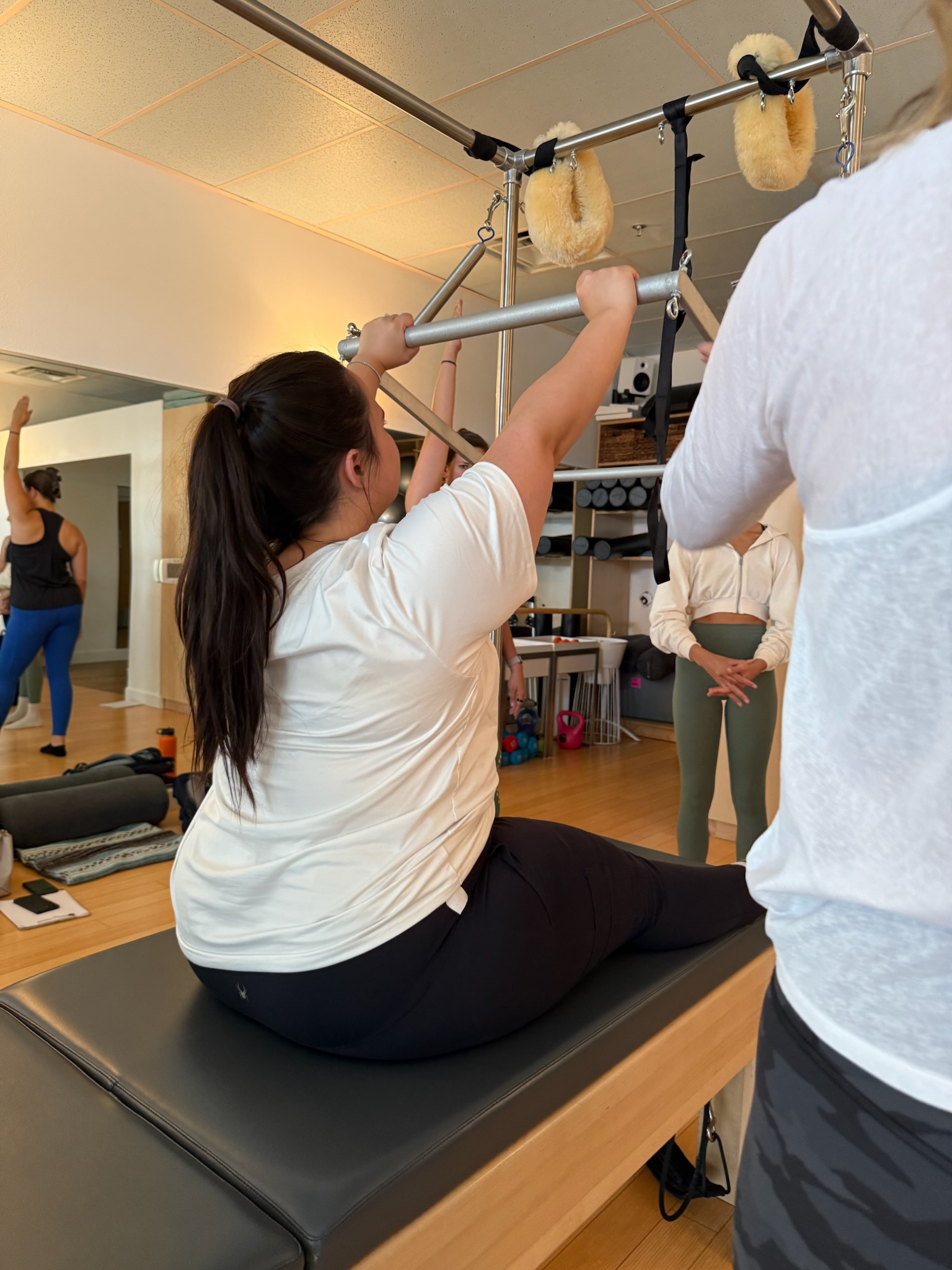 Pilates Teacher Training students practicing push thru on the Cadillac/trapeze table