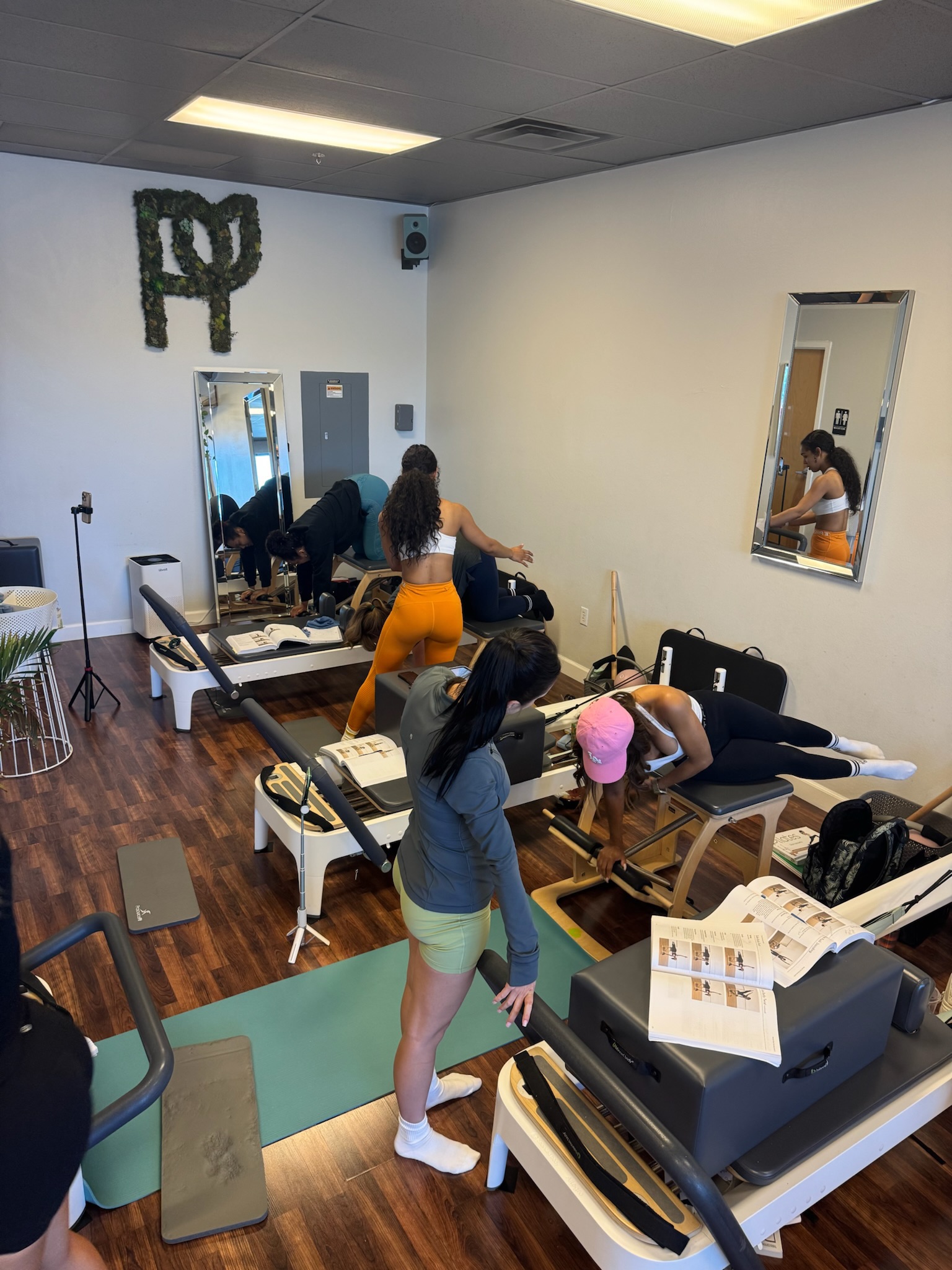 Pilates Teacher Training students practicing teaching each other on the wunda chair