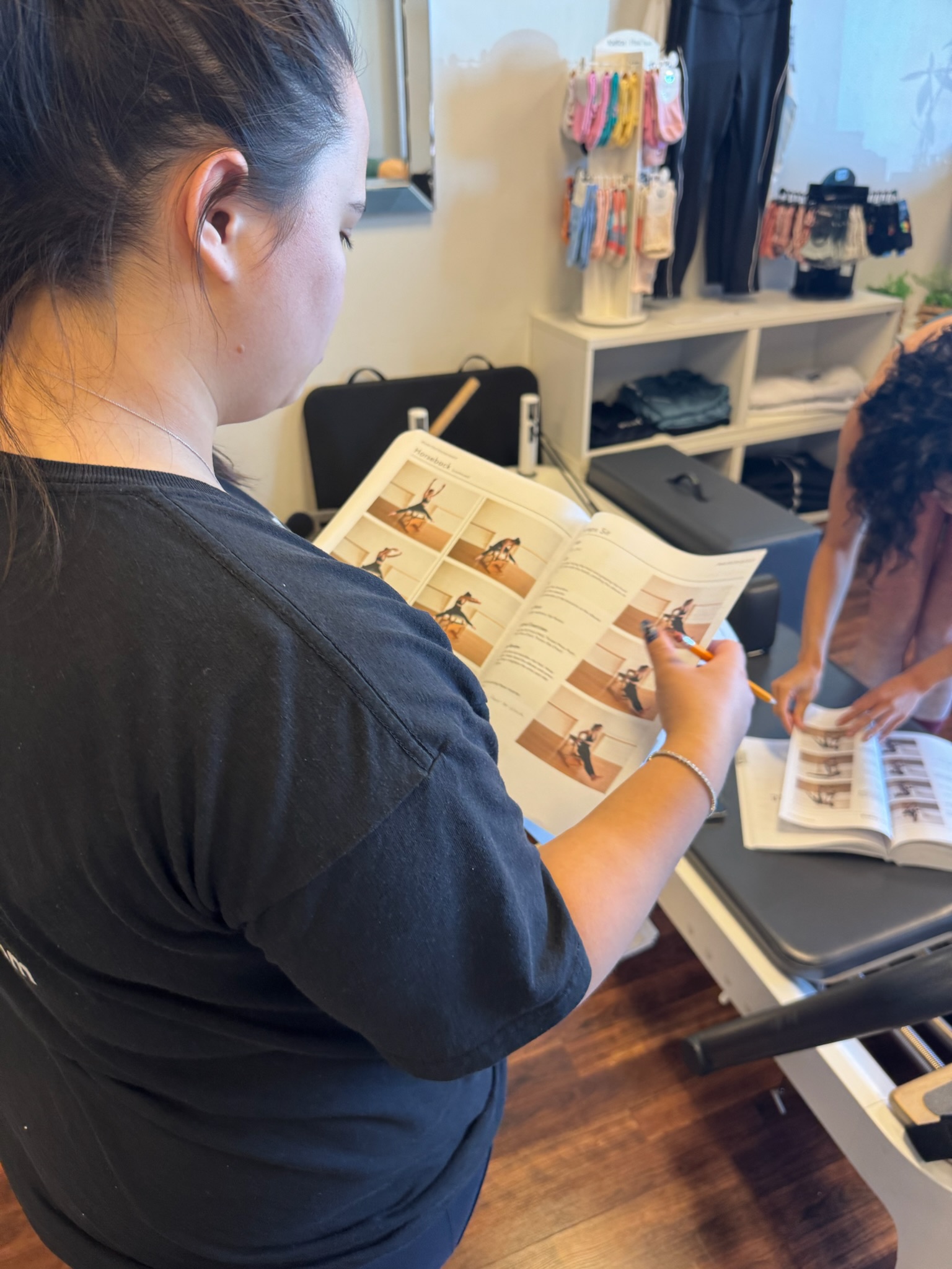 Pilates Teacher Training student reading manual on reformer